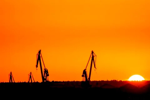Landscape of a cranes in a harbor at sunset with clouds Stock Photos