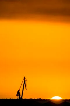 Landscape of a cranes in a harbor at sunset with clouds Stock Photos