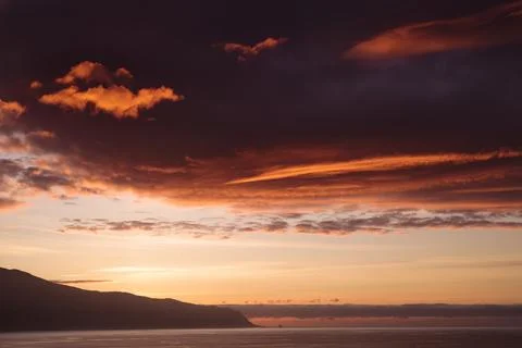 Landscape with dramatic clouds over the ocean, orange sunset Stock Photos