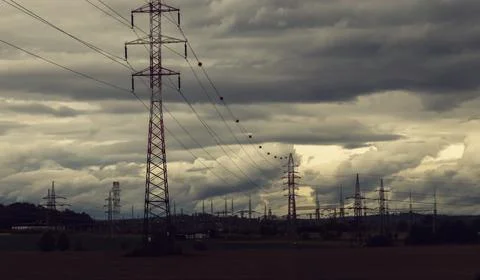 Landscape with dramatic overcast sky, high voltage pylons Stock Photos