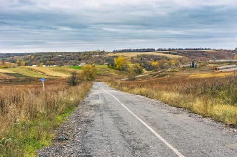 Landscape with an empty rural road at cloudy autumnal day in Sumskaya oblast Stock Photos