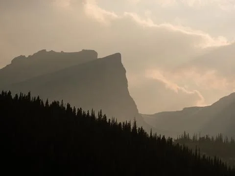 Landscape of forest silhouette and dramatic light shining on ridges of Rock M Stock Photos