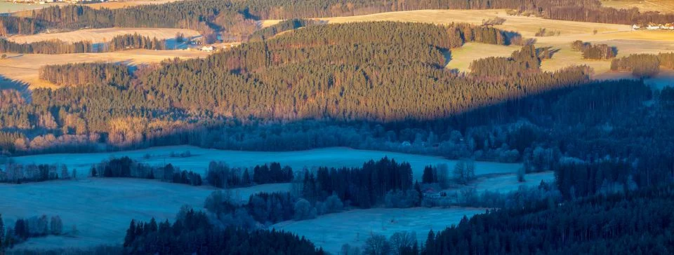 Landscape with forests and meadows - half shaded and half lit by the sun Stock Photos