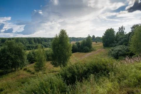 Landscape with forests and small meadows and a beautiful cloudy sky. Stock Photos
