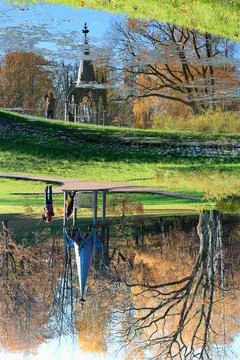 Landscape with a gothic tower reflected in a pond and tourists posing 写真素材