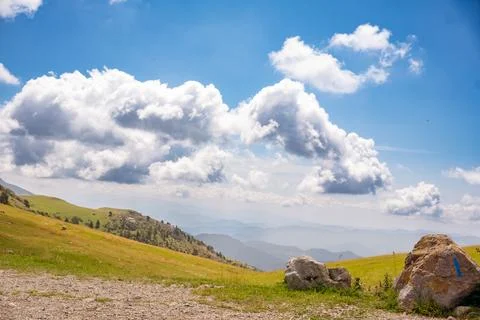 Landscape of green meadows between mountains, with a blue sky with clouds. Stock Photos