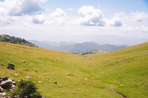 Landscape of green meadows between mountains, with a blue sky with clouds. Stock Photos