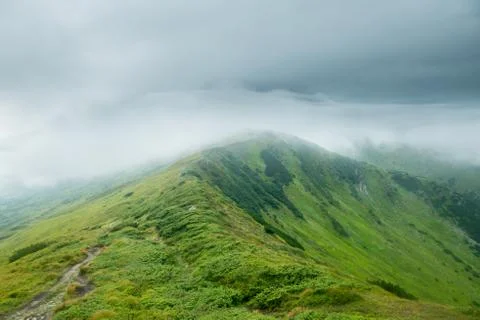Landscape with green mountains in the clouds Stock Photos