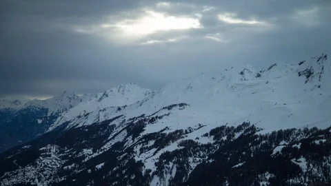 Landscape of heavy clouds moving across sky as sunshine beams above mountains Video stock 129100200