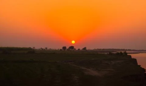 Landscape image of sun set on green fields Stock Photos