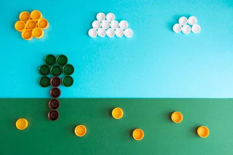 Landscape made of plastic bottle caps. Green grass, blue sky, sun and clouds Stock Photos