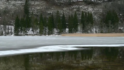 Landscape of mountain, forest and half frozen lake. Reflection in water. Stock Footage 247467416