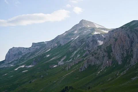 Landscape with a mountain range surrounded by green alpine meadows. Stock Photos