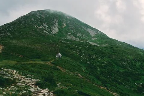 A landscape of a mountainous area covered with grass and stones. House among  Stock Photos