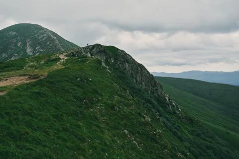 A landscape of a mountainous area covered with grass and stones. In the dista Stock Photos