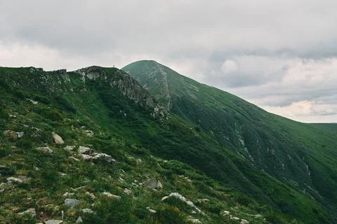 A landscape of a mountainous area covered with grass and stones. In the dista Stock Photos