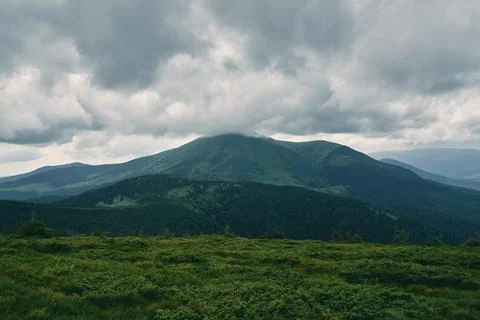 A landscape of a mountainous area covered with grass and stones. Cloudy mount Stock Photos