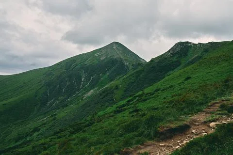 A landscape of a mountainous area covered with grass and stones. Cloudy mount Stock Photos