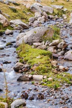 Landscape with mountains and a stream in the foreground. Stock Photos