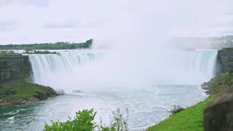 Landscape of Niagara Falls showcasing powerful flow of water, lush greenery mist 스톡 동영상 292604427