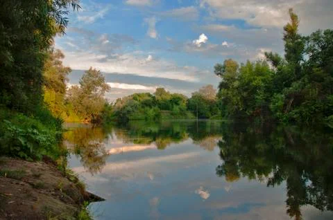 Landscape with river, forest, clouds and reflection. Stock Photos