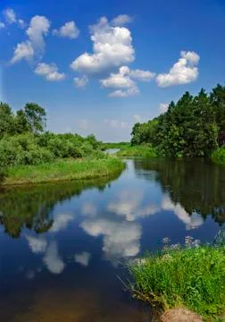Landscape with river, forest, clouds and the reflection in the water. Stock Photos