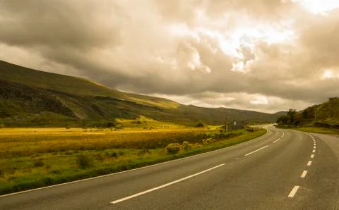 Landscape road in mountains under cloudy sky Stock Photos