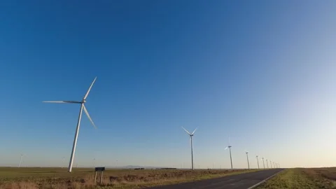 Landscape with a road in perspective with electricity-generating windmills .. Stock Footage 252399097