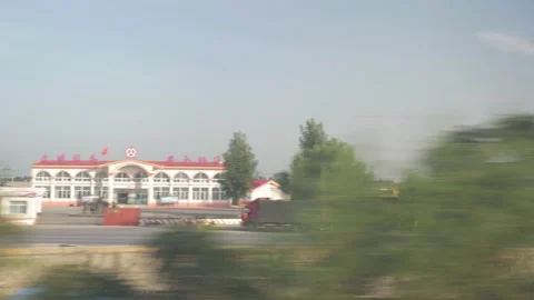 The landscape scrolls from a train with cities and trees, in China Stock Footage 232198656