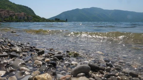 Landscape shooting of pebbles, oncoming waves and mountains. Stock Footage 89486852