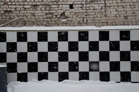 Landscape shot of a wall with a chess pattern on a snowy day Stock Photos