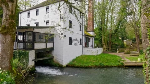Landscape showing old white washed water mill with mill pond and woodland s.. Stockbeeldmateriaal 239637949