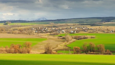 Landscape in spring. Dark rain clouds and green meadows. Village in sunlight Stock Footage 105012871