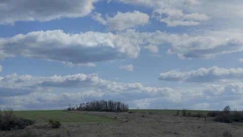 Landscape with a spring field and thick clouds Stock Photos