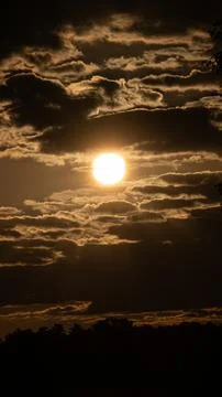 Landscape with sun setting behind dark clouds Stock Photos