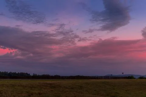 Landscape sunset with fully colored clouds pink orange sky look on meadow clo Stock-Fotos