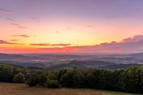 Landscape sunset with fully colored clouds pink orange sky look on meadow clo Stockfoto's