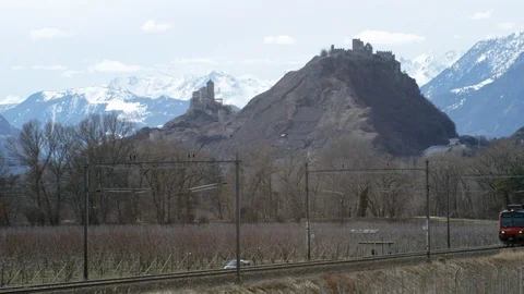 Landscape of train passing by fenced castle ruins of tourbillon on cloudy day Stock Footage 129094831