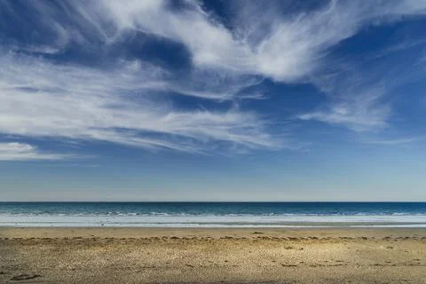 Landscape of an uncrowded beach with white clouds over blue sky. Stock Photos