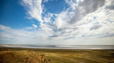 The landscape is vast with dramatic clouds and a blue sky, conveying peace and Stock Photos