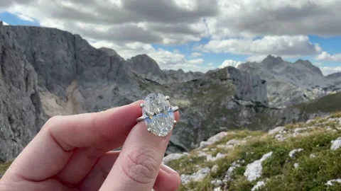 Landscape video capturing shimmering oval diamond engagement ring and mountains Video stock 319442140