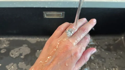 Landscape video of oval diamond ring shining while rinsed in modern kitchen sink Video stock 316598942
