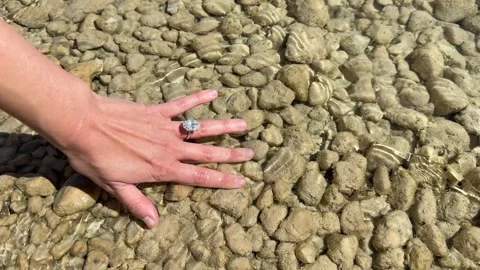 Landscape video ring hand moving across pebble surface in daylight Stock Footage 319402731