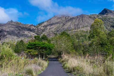 A landscape view of cloud covered Mount Batur from the road at the botom Stock Photos