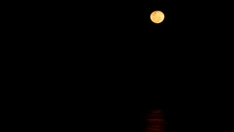 Landscape view of a golden orange full moon with lunar craters shining and Stock Footage 345182620