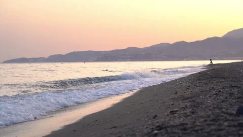 Landscape view of a kid playing alone in the distance at a gorgeous beach dur Stock Footage 137017973