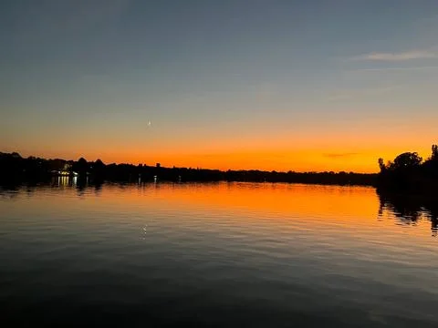 Landscape view reddish sunset with moon reflecting on lake Foto stock