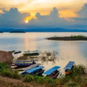 Landscape view of sunset and long-tailed boats carrying tourists in a row in  Stock Photos