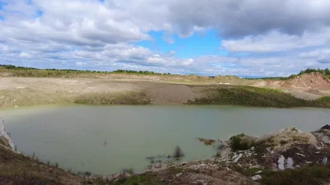Landscape view of a water-filled pit surrounded by grassy slopes and scattered c Stockbeeldmateriaal 340448236