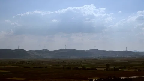 Landscape view of wind turbines over the hills spinning and clouds passing Stock Footage 82095127